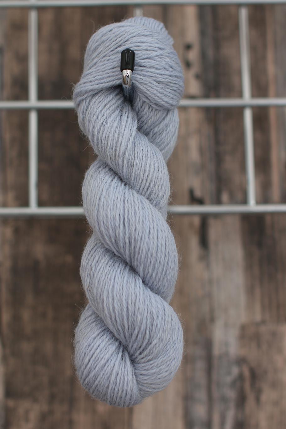 A single skein of pale blue wool hanging from a hook