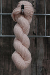 a single skein of pale pink wool hanging from a hook