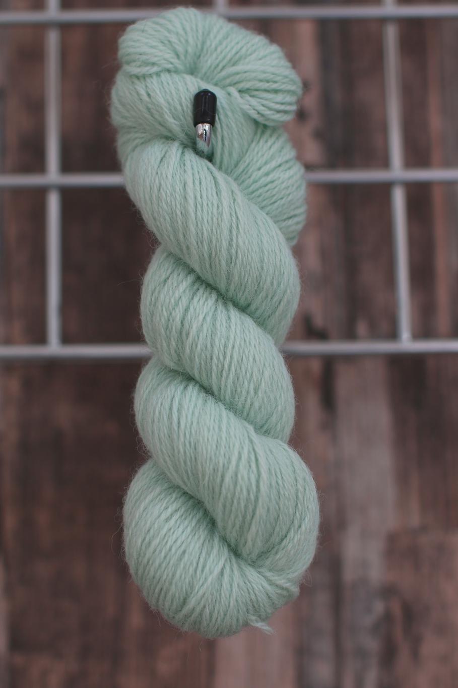a single skein of mint coloured wool hanging from a hook