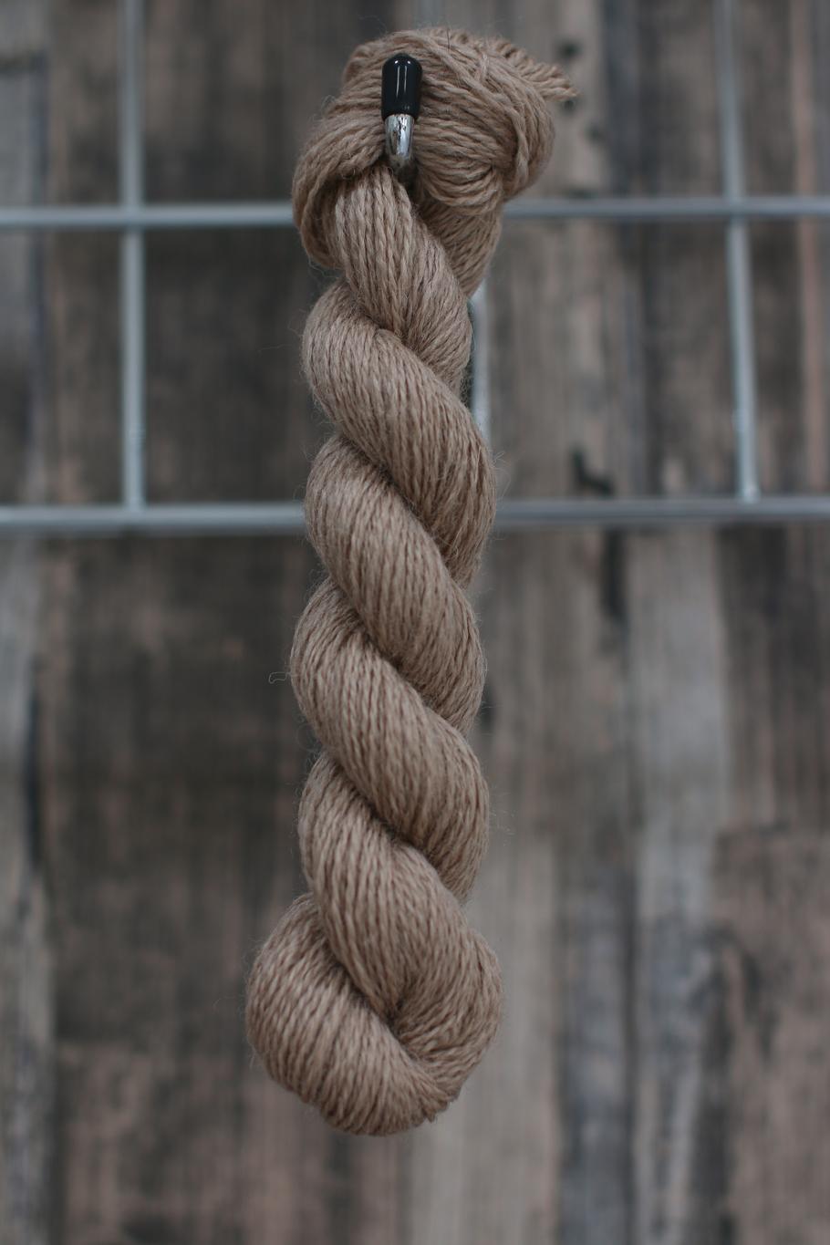 a greyish-beige skein of wool hanging from a hook
