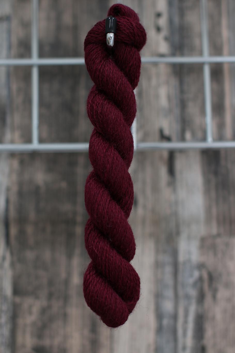 a skein of  damson coloured wool hanging from a hook