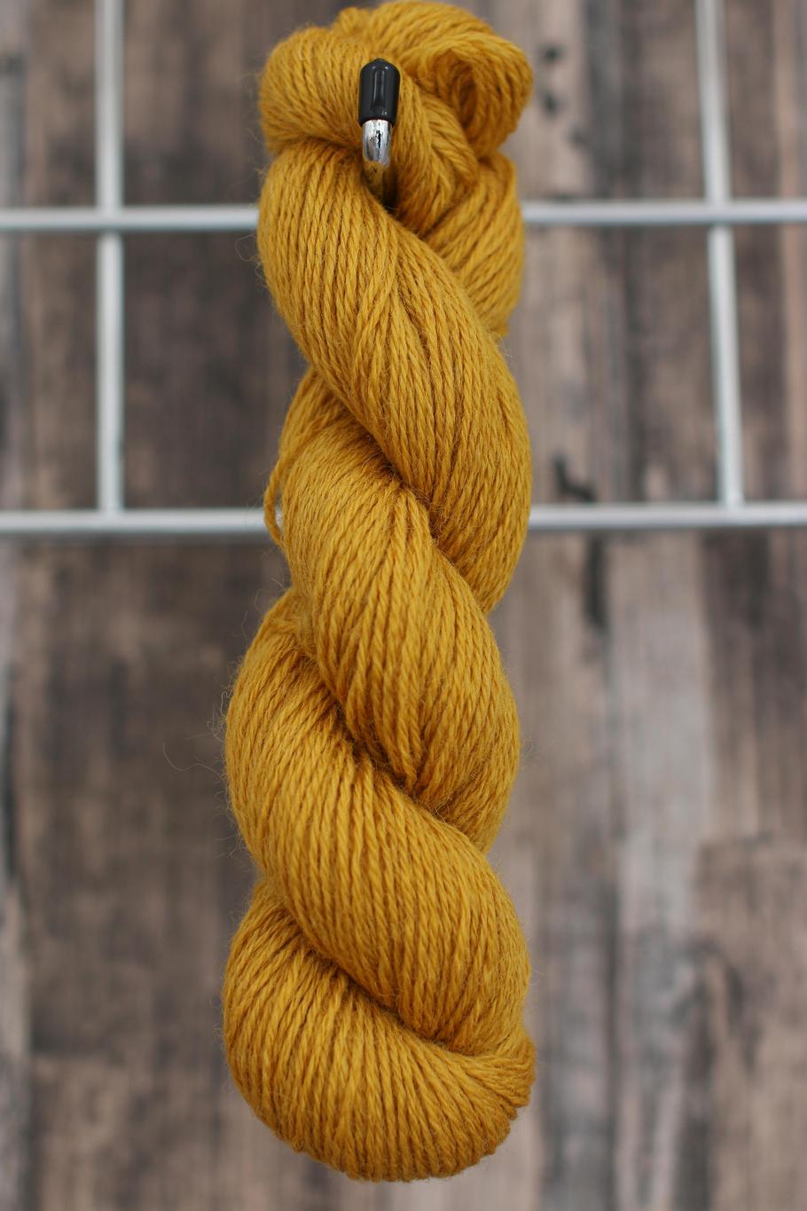 a golden yellow skein of wool hanging from a hook