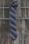 A single skein of grey wool hangs from a hook