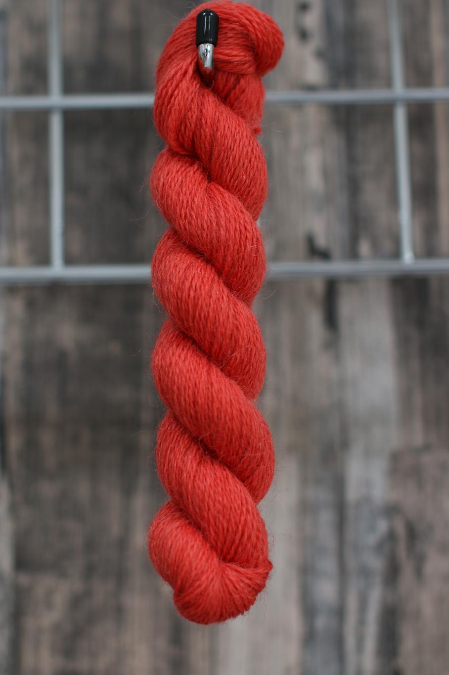 a single skein of red wool hanging from a hook