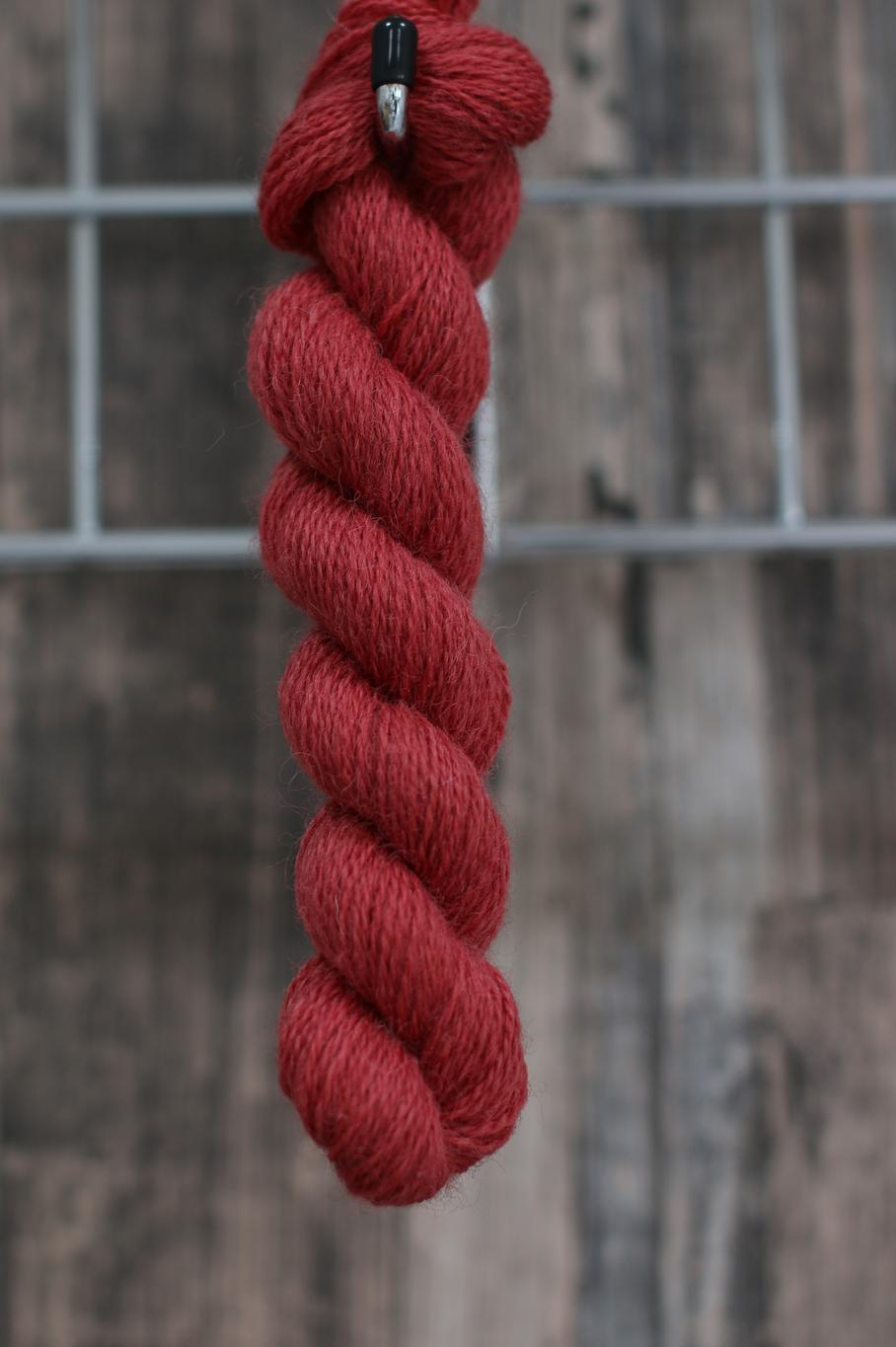 a single skein of red wool hanging from a hook