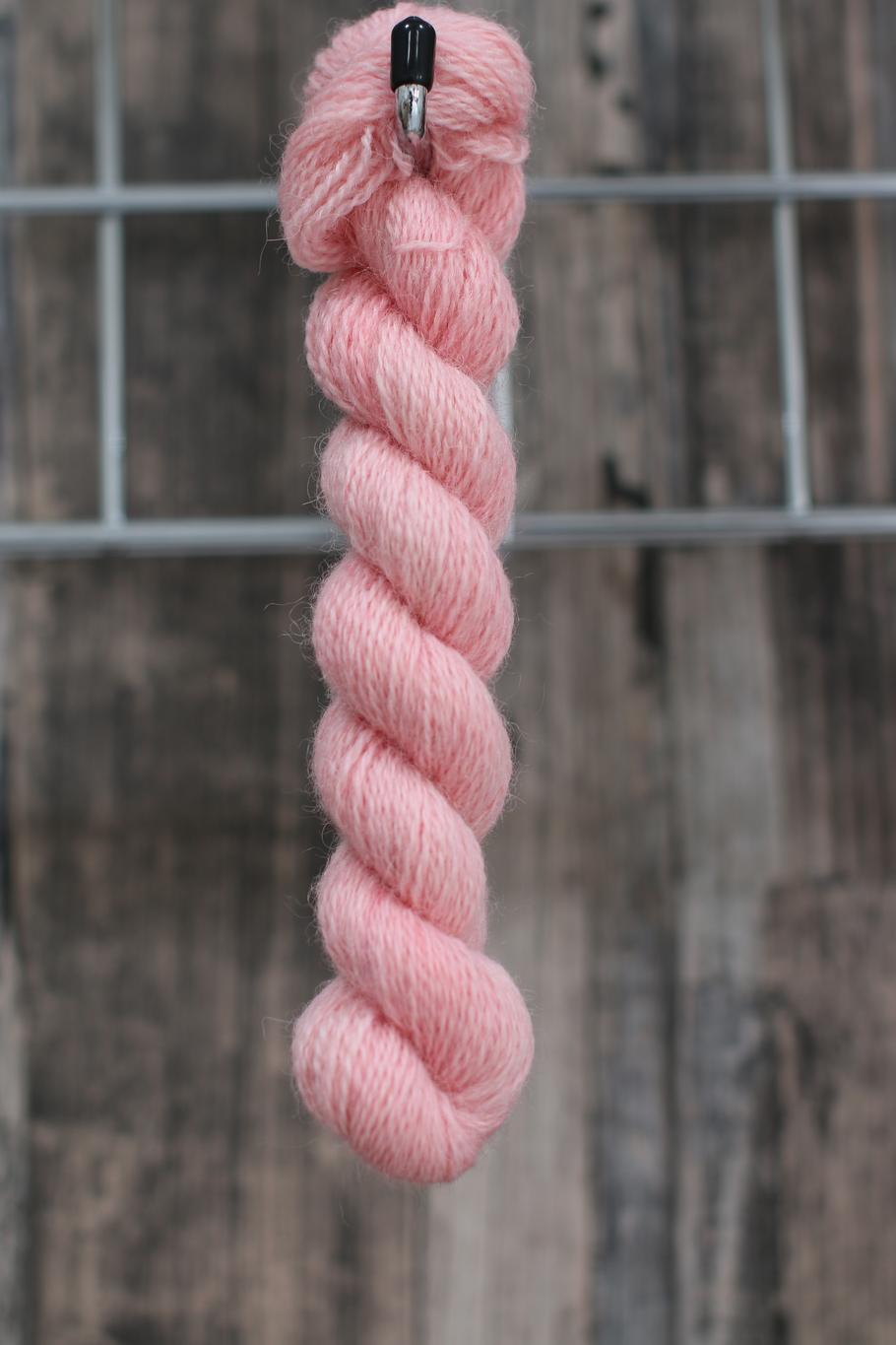 a skein of pink wool hanging from a hook