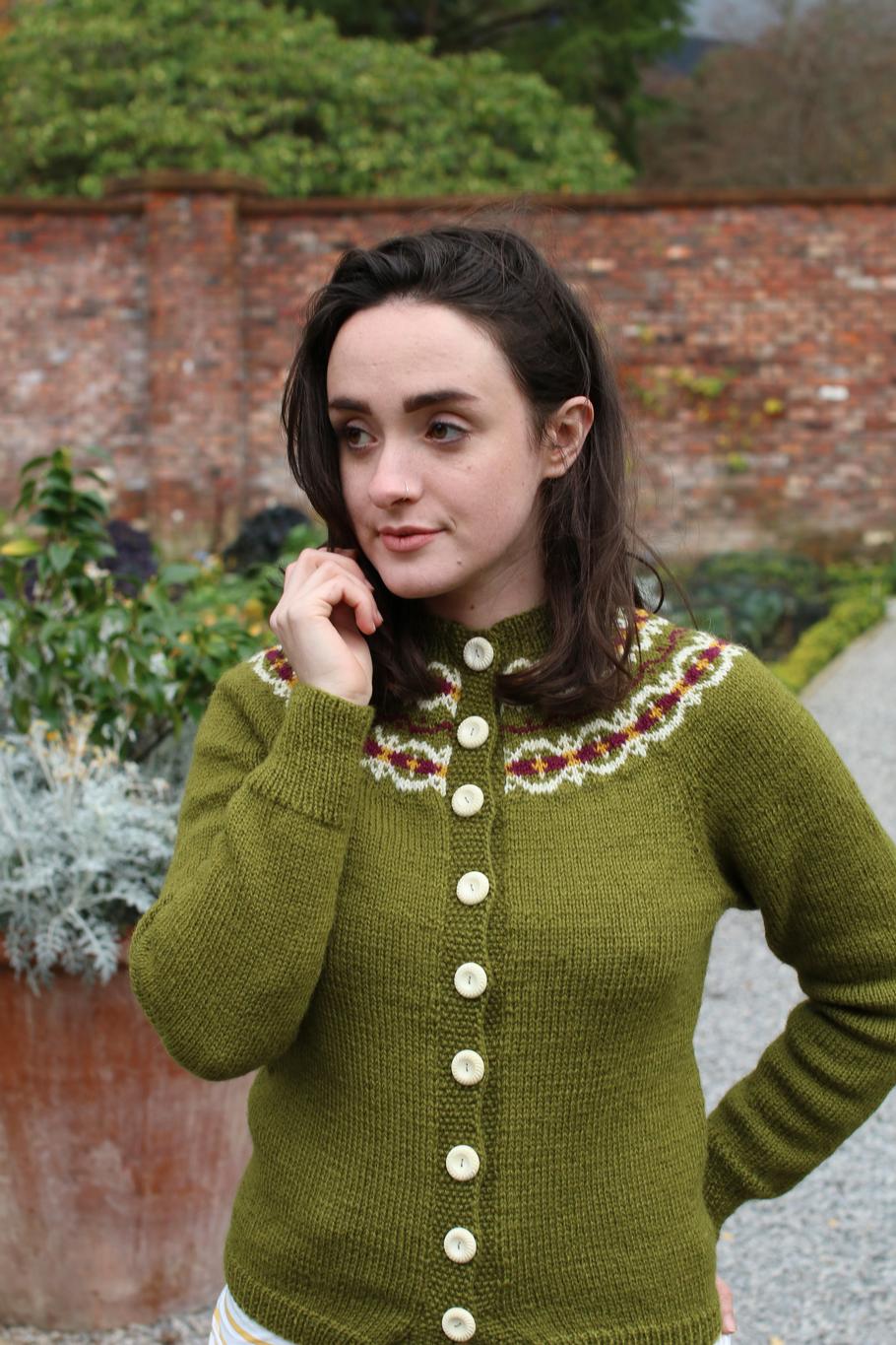 A girl in a green cardigan with a decorative yoke in three contrasting colours