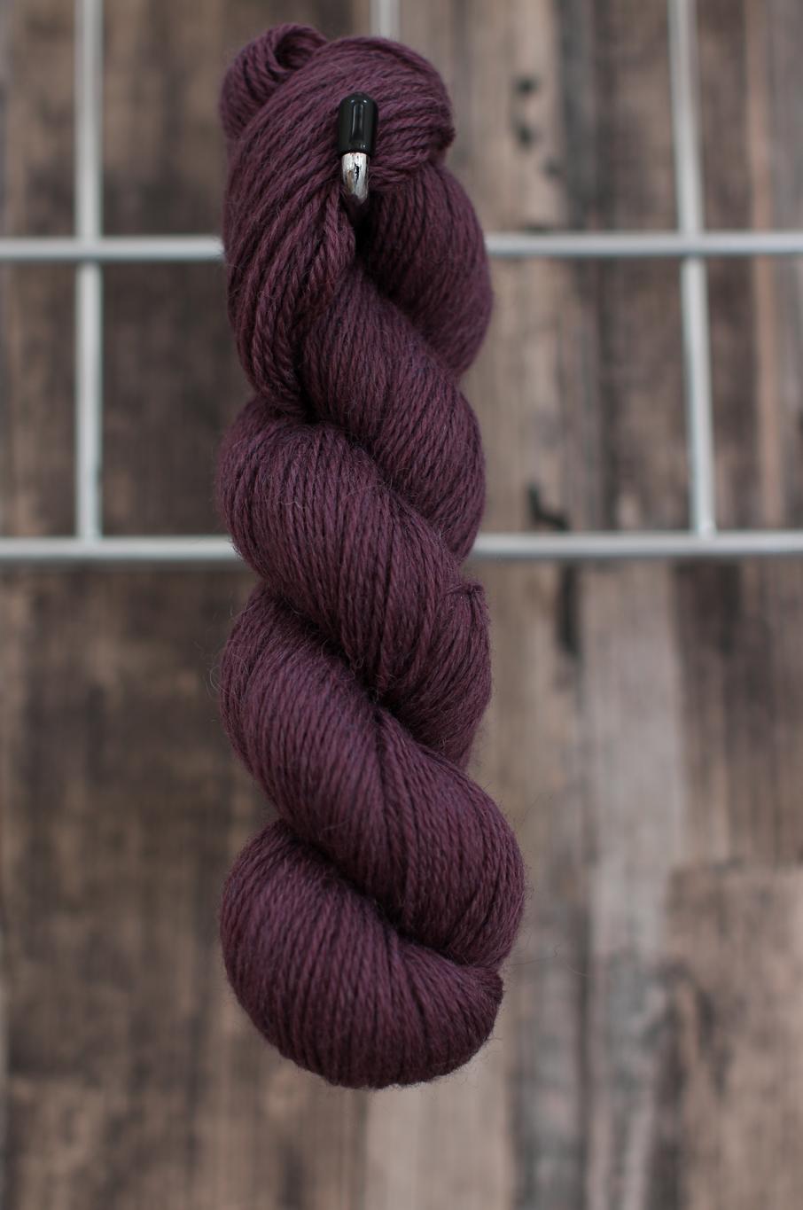 A single skein of purple wool hanging on a hook