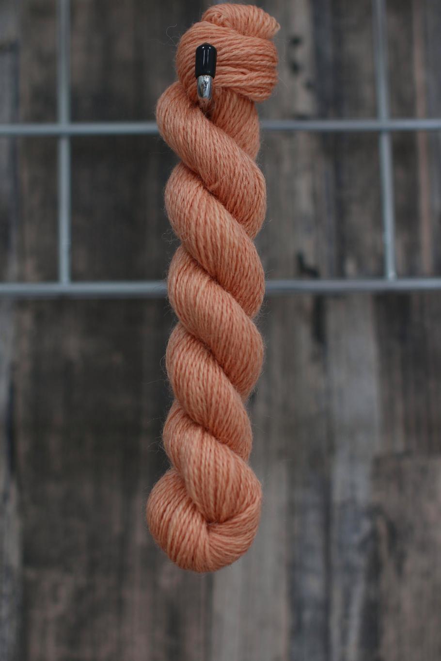 a skein of peach wool hanging from a hook