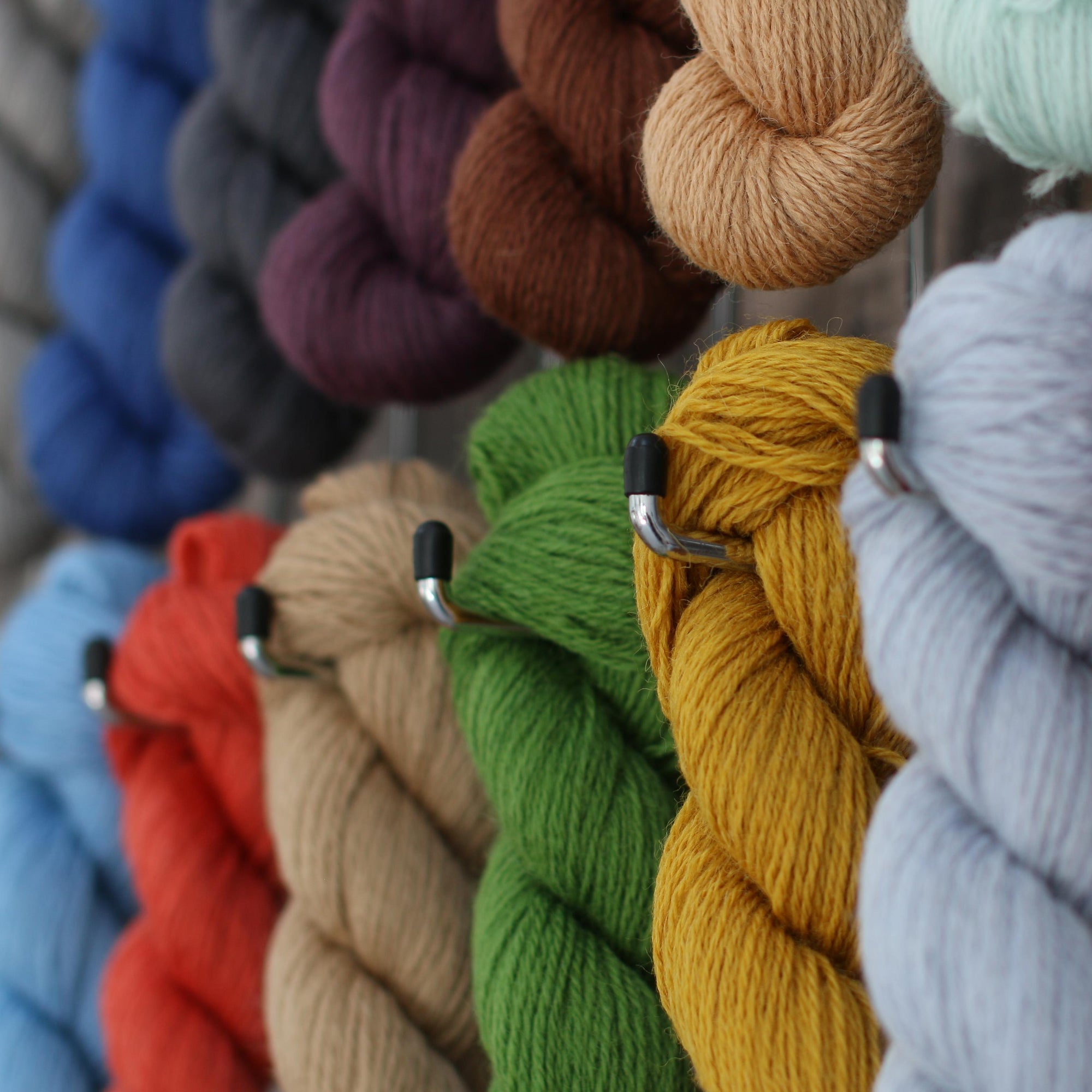 several skeins of wool all different colours hanging from hooks