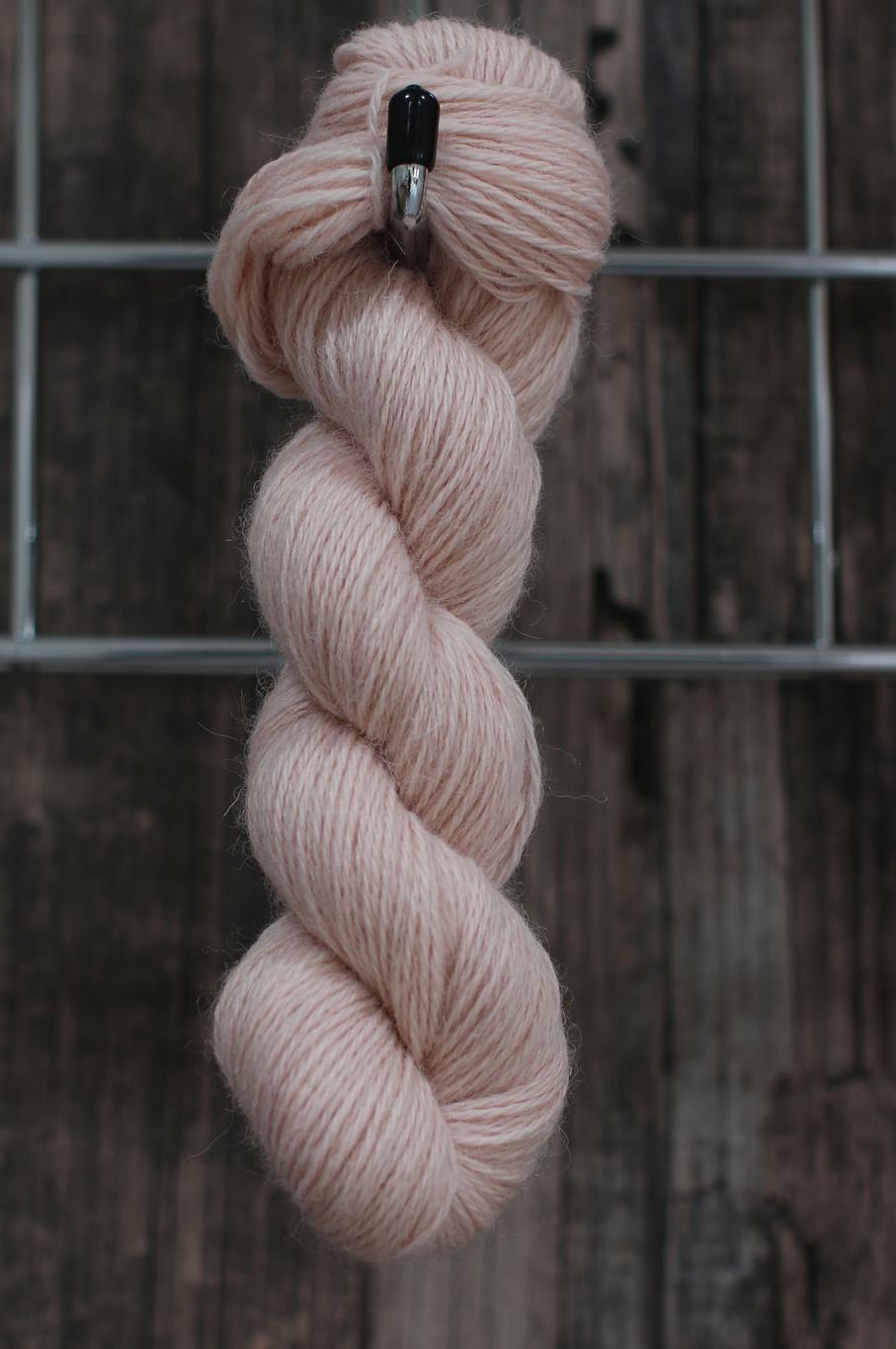 a single skein of pale pink wool hanging from a hook