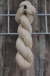 A single skein of oatmeal wool hanging from a hook