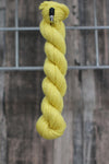 A bright lemon skein of wool hanging from a hook