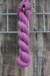 a deep pink skein of wool hanging from a hook
