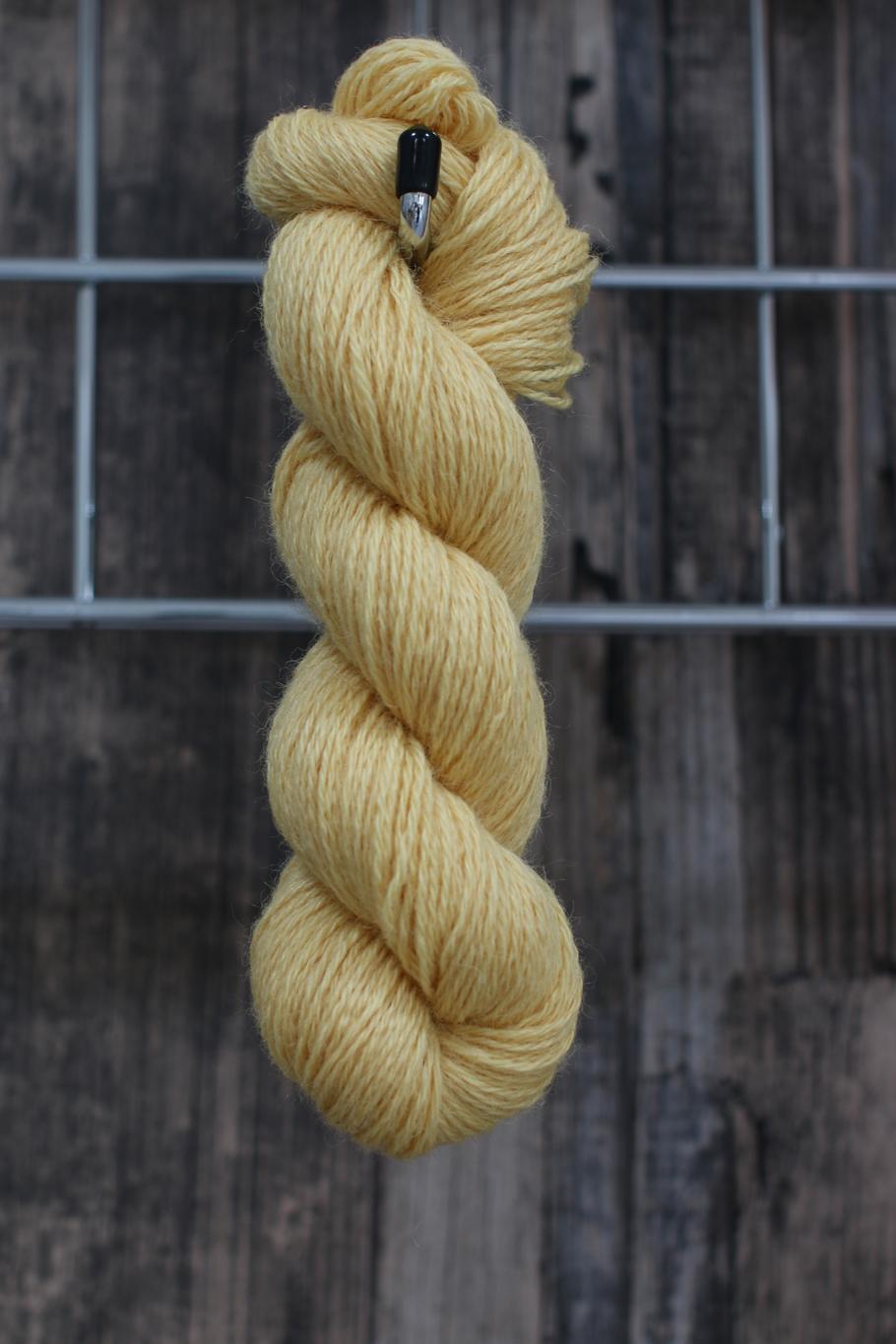 A soft yellow skein of wool hanging from a hook