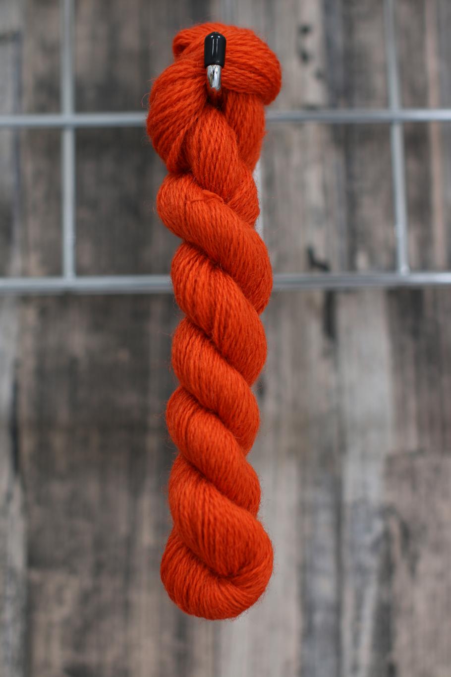 an orange skein of wool hung on a hook