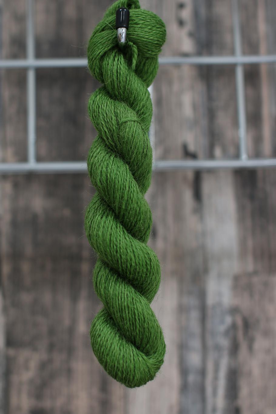 A leaf-green skein of wool hanging from a hook