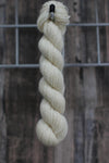 a skein of natural white undyed wool hanging from a hook
