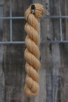 a straw coloured skein of wool hanging from a hook